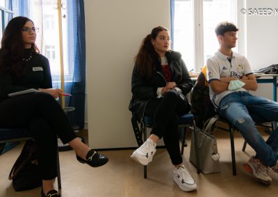 Drei Menschen auf Stühlen im Seminarraum