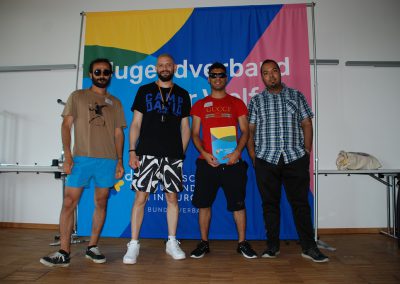 Vier Männer posieren vor dem Banner "Jugendverband der Vielfalt"