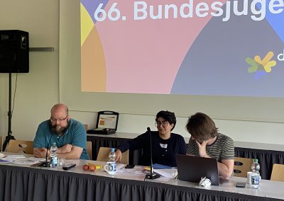 Auf dem Podium sitzen drei Menschen